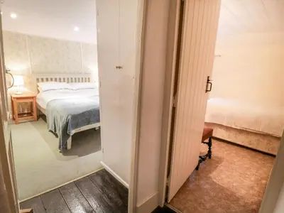 a room with a bed and a door leading to a bedroom at 2 Rose Cottages in Looe