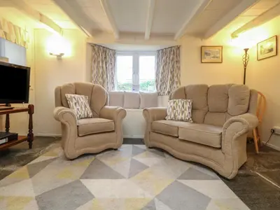 a living room with two chairs and a television at 2 Rose Cottages in Looe