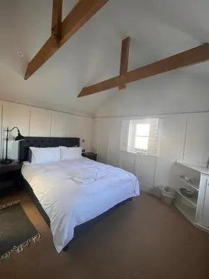 a bedroom with a large white bed with a ceiling at The Thirsty Scholar in Penryn