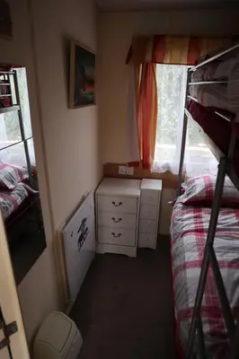a small bedroom with a bunk bed and a window at Kimberley Lane Static, Cornwall in Gwennap
