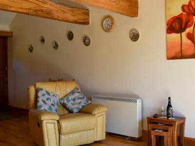 a living room with a chair and a clock on the wall at Round House - Uk12083 in Saint Endellion