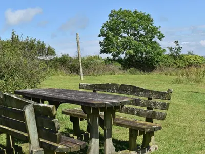 a wooden table and bench in a field at Swallows Nest - Uk12085 in Saint Endellion