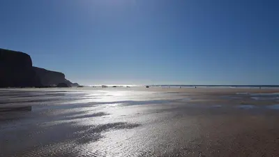 a view of a beach with the ocean in the background at The Wriggly Tin & Baa Spa at Tregoose Old Mill in Newquay