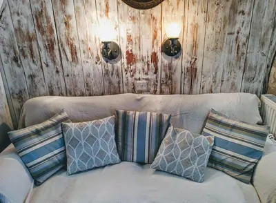 a white couch with pillows on it with wooden walls at Truly Paradise Cottage in Golant