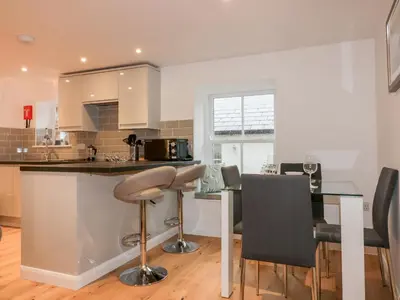 a kitchen with a counter and a bar with chairs at Captain's Cabin in St Austell