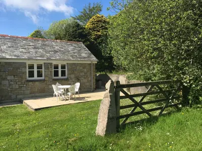 a cottage with a table and chairs in front of it at Little Pengelly Farm in Crowan