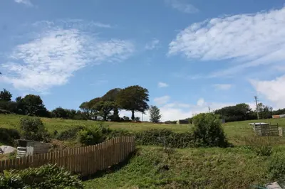 a fence in a field with a blue sky at Kerryanna Country House Bed and Breakfast in Mevagissey