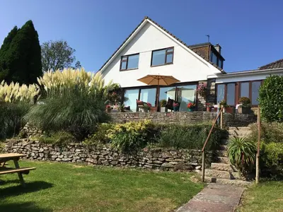 a house with a stone wall and an umbrella at Kerryanna Country House Bed and Breakfast in Mevagissey