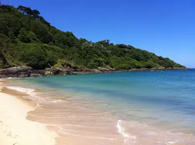 a beach with clear blue water and a mountain at Seaside Apartment in Carbis Bay