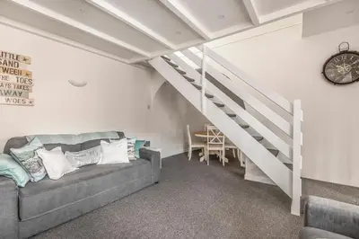 a living room with a couch and a staircase at Lime Kiln Cottage, Pentewan, Cornwall in Pentewan