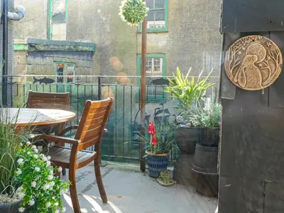a patio with a table and chairs and plants at Talland House in Polperro