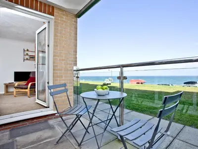 a patio with a table and chairs and the ocean at Apartment 2 Waters Edge in Crantock