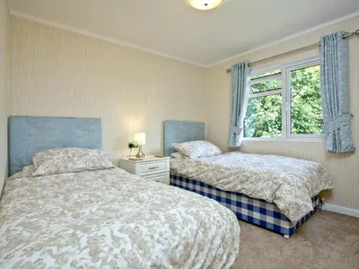 a bedroom with two beds and a window at Forest Glade Lodge in Lanlivery