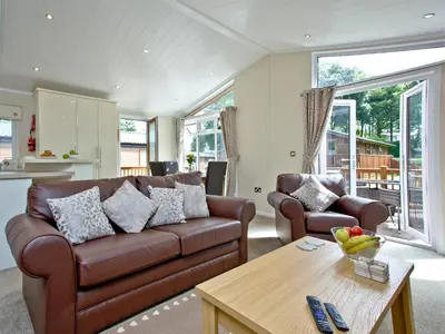a living room with a brown couch and a table at Forest Glade Lodge in Lanlivery