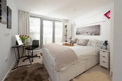 a white bedroom with a large bed and a desk at Fistral Beach Penthouse, Newquay in Crantock