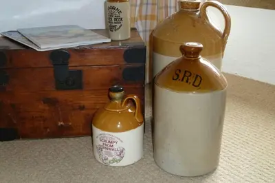 two glass bottles are sitting next to a chest at The Snug at Cornish Barn Holidays in Truro
