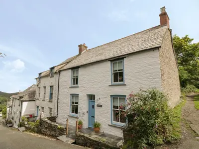 a white house with a blue door on a street at Fairfield Cottage in Boscastle