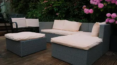 two wicker chairs with pillows on a patio with flowers at Commanders Cabin 'As seen in Beyond Paradise' in Looe