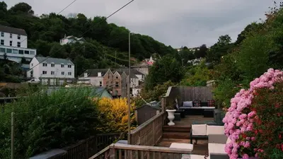 a wooden deck with chairs and flowers in a town at Captain's Quarters 'As seen in Beyond Paradise ' in Looe