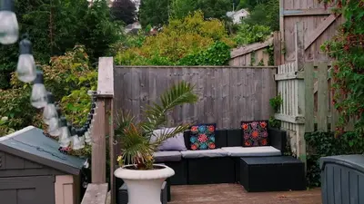 a patio with a bench with pillows on a fence at Captain's Quarters 'As seen in Beyond Paradise ' in Looe