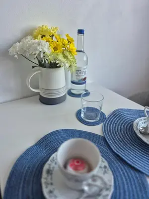 a table with a cup of coffee and a vase of flowers at Number 6 in St Austell