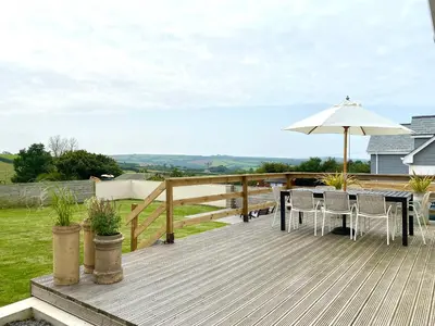 a wooden deck with a table and an umbrella at Auverne in Bude