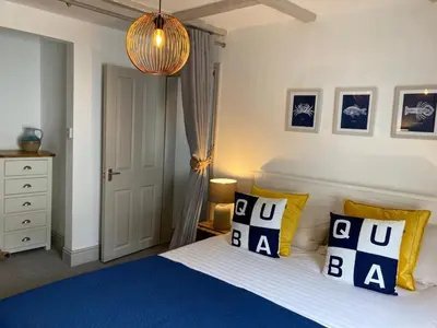 a bedroom with a bed with blue and yellow pillows at On Season 4 of BBC 1s BEYOND PARADISE - Prospect House is TWO PRIVATE APARTMENTS in this 17th CENTURY COTTAGE - Apartment 2 has a KIDS CABIN BUNK ROOM - Book both apartments for ONE LARGE HOUSE with Connecting Door In Lobby - FREE PUBLIC PARKING OUTSIDE in Looe