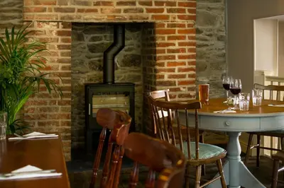 a fireplace in a dining room with a table and a stove at Seven Stars Penryn in Penryn