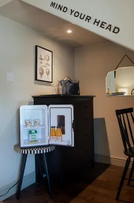 a small refrigerator sitting on a stool in a room at Seven Stars Penryn in Penryn