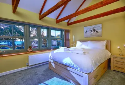 a bedroom with a large bed in a room with windows at The Old Smoke House in St Austell