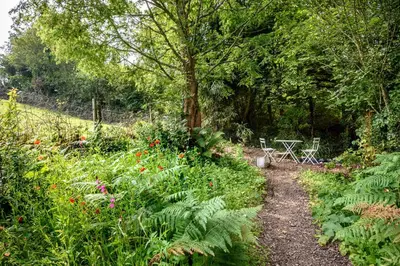 a garden path with plants and a table in the background at Luxury Coastal Shepherds Hut with hot tub, dining dome & a 5 Minute Walk to Pubs and Village in Polperro