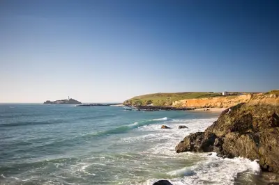a beach with rocks and the ocean on a sunny day at Towennan - four bedroomed apartment in quiet seaside village. in Gwithian