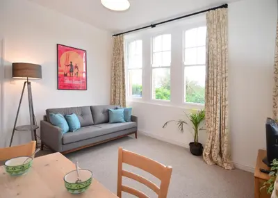 a living room with a couch and a table at Towennan - four bedroomed apartment in quiet seaside village. in Gwithian