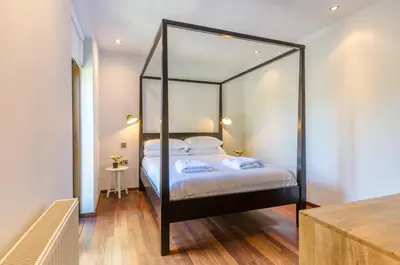 a bedroom with a black canopy bed with a mirror at Charming Summerhouse Annexe in lush gardens in Fowey in Fowey