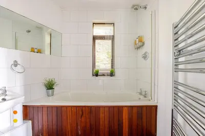 a white bathroom with a tub and a window at Charming Summerhouse Annexe in lush gardens in Fowey in Fowey