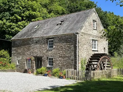an old stone building with a wooden fence at Jopes Mill and Lodge in Looe