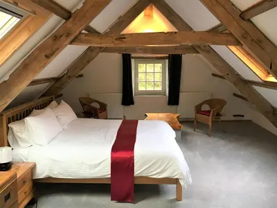 a bedroom with a white bed in a attic at Jopes Mill and Lodge in Looe