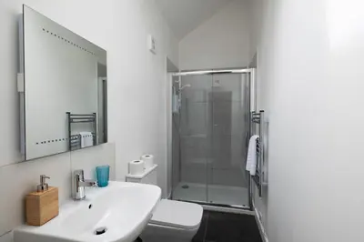 a white bathroom with a shower and a sink at Jopes Mill and Lodge in Looe