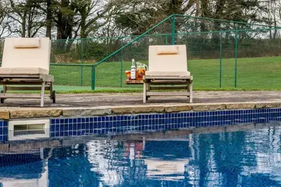 two chairs sitting next to a swimming pool at The Manor House at Boconnion in Bodmin