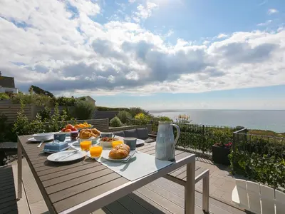 a table with food on top of a balcony with the ocean at Sea Sands in Penzance