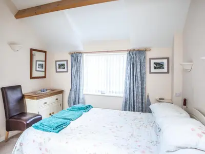 a bedroom with a bed and a chair and a window at The Old Store House in Boscastle
