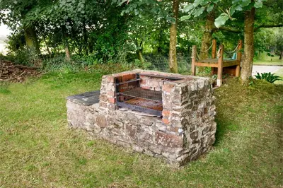 a brick oven in the grass next to a bench at Pond Meadow in Launceston