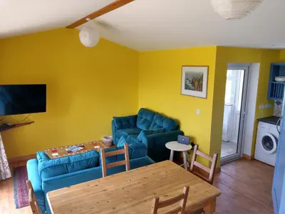 a living room with a blue couch and a table at Orchard Chalet in Liskeard