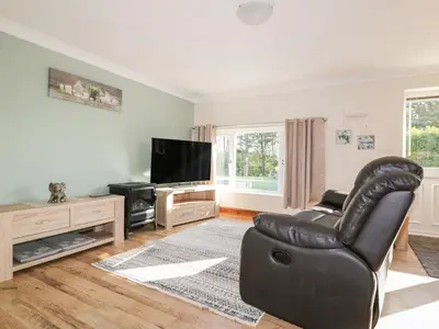 a living room with a leather chair and a flat screen tv at Lower Brambleside in Truro