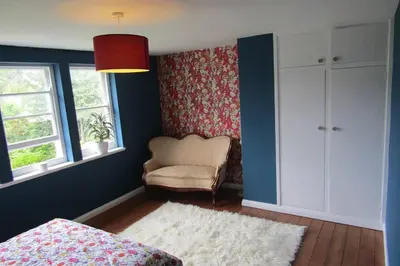 a bedroom with a bed and a chair and windows at Lovely 3 Bed House Close to Carlyon Bay Beach! in Carlyon Bay