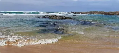 a beach with some waves and rocks in the water at 2-Bed Cottage Sleeps 5 Pets Ok Close to Coast in Davidstow