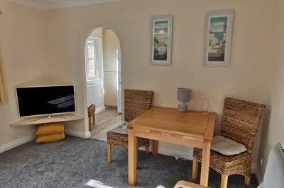 a living room with a television and a table and chairs at The Honeypot - Cornish Apartment close to Eden Project & beaches in Par