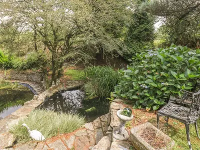 a bench sitting next to a pond in a garden at Trevenna Cabin in St Austell