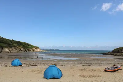 two tents on a sandy beach next to the ocean at Owls Roost in Falmouth