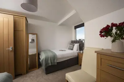 a bedroom with a bed and a vase of flowers at Bridge Apartment - Free Parking & WiFi - Near Perranporth Beach in Perranporth
